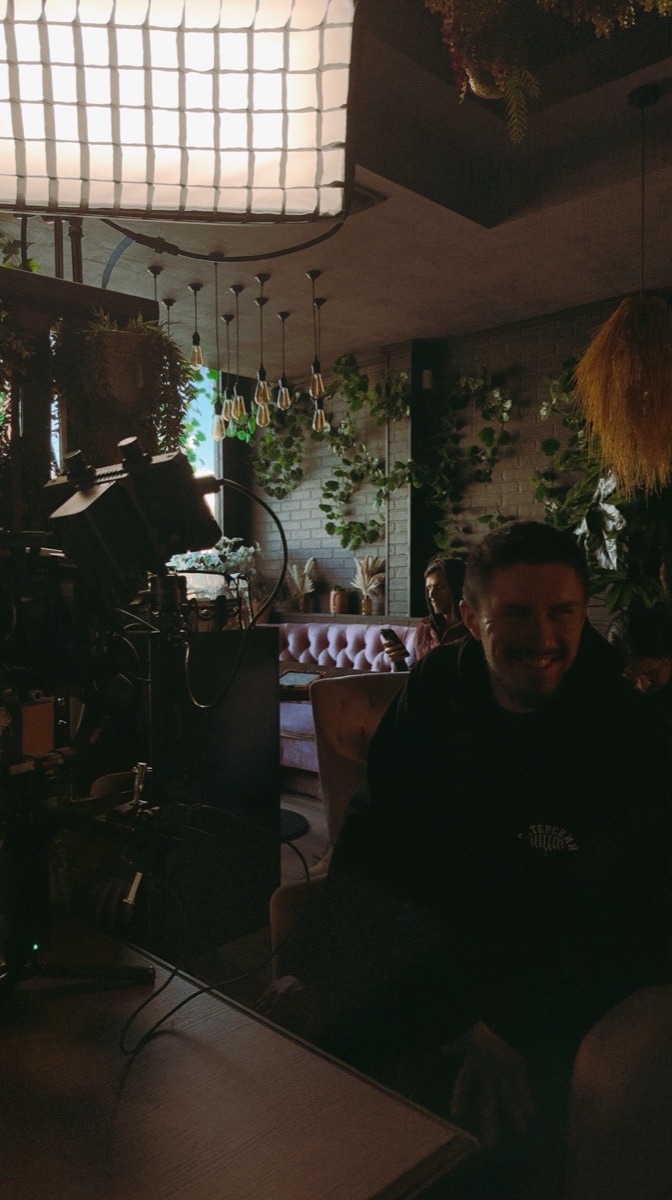 Crew on set in a restaurant, lighting rig and monitor in frame